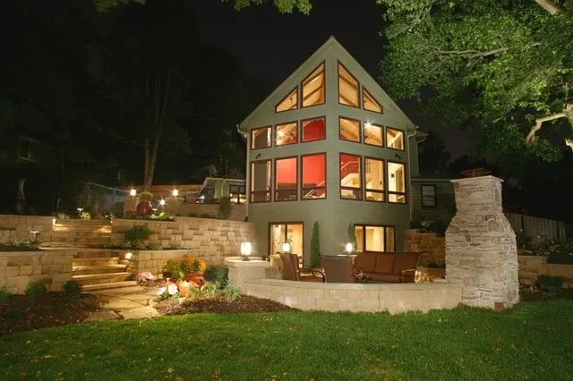 Modern multi-story home with illuminated landscaping and facade