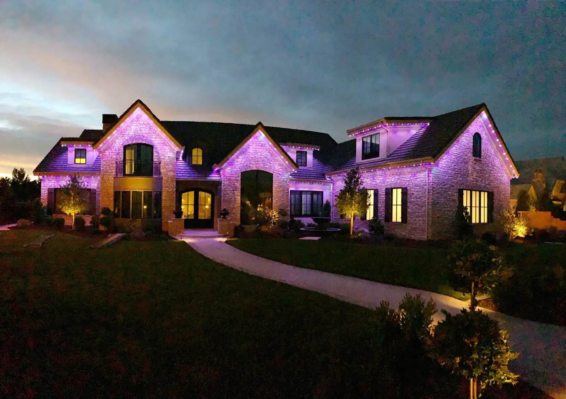 Large home with purple roofline lighting and landscape lighting